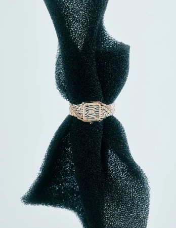 Close-up of an animal print buckle bracelet on dark porous sponge with studio lighting, showcasing jewelry design.