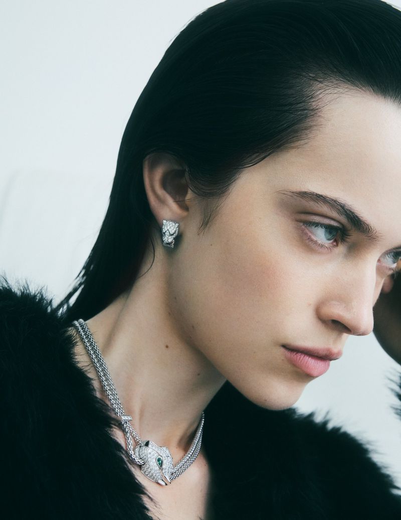 Portrait of woman wearing a silver panther necklace and earrings against a white backdrop, jewelry design, fashion photography.