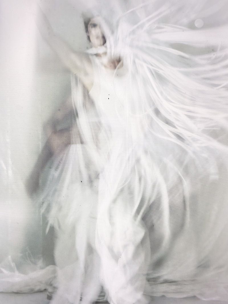 Woman in flowing white dress with motion blur. Soft, ethereal effect, creating a sense of movement, beauty, and fluidity in studio environment.