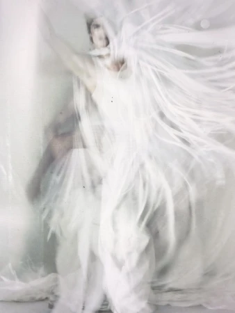 Woman in flowing white dress with motion blur. Soft, ethereal effect, creating a sense of movement, beauty, and fluidity in studio environment.
