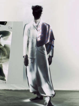 Man stands in a photo studio wearing a pale suit with purple cloth draped over shoulder, obscured face, surreal and artistic image.
