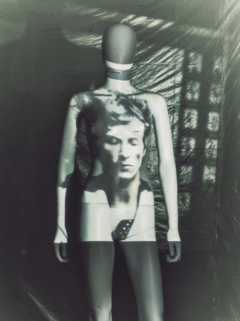 Mannequin with face projection stands in a photo studio with lighting and shadow play, creating an artful, monochrome fashion-forward visual.