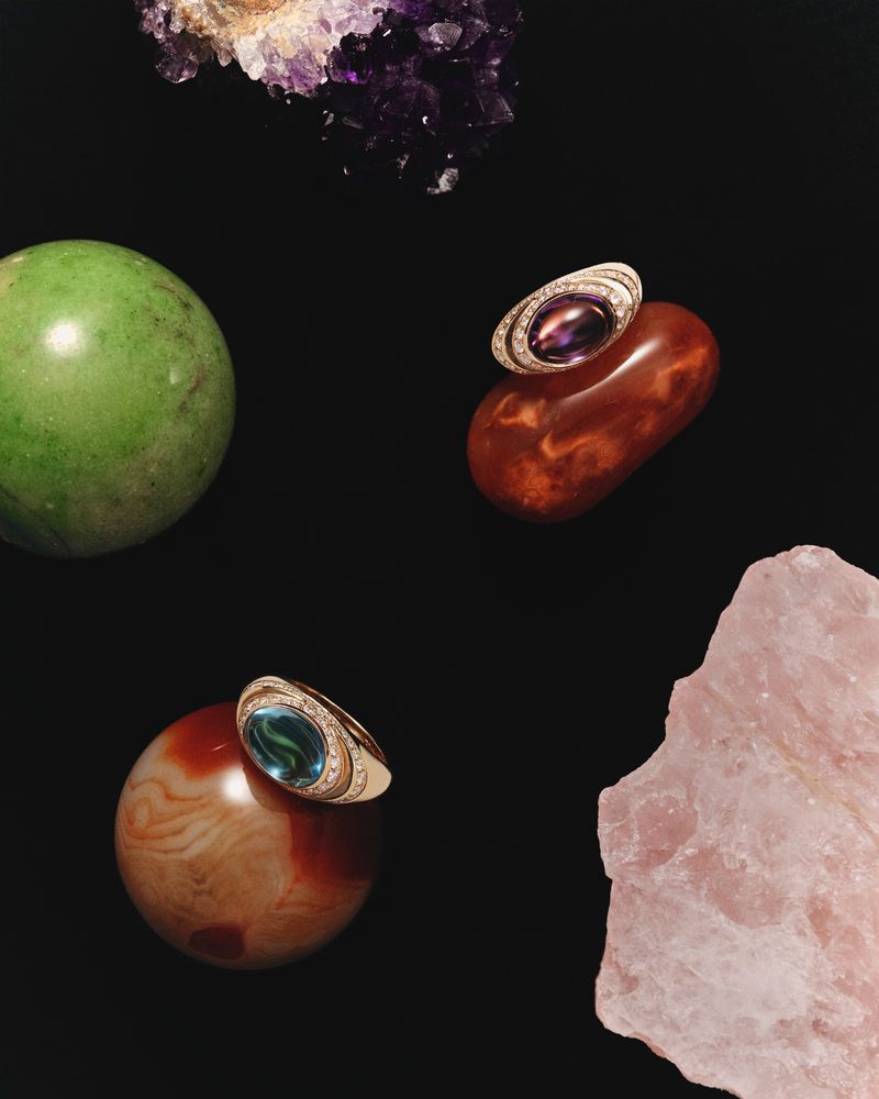 Still life studio shot of two gemstone rings on colorful rocks against black background. Jewelry advertisement, fashion photography.