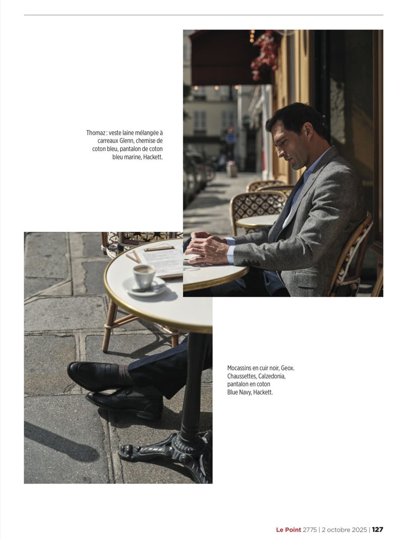 Man in a blazer sitting at an outdoor cafe table with coffee and a document, bathed in warm sunlight, with a city street background.