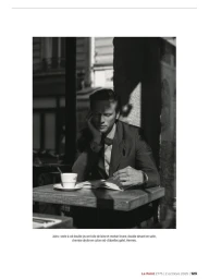Black and white photograph of model Jules Raynal seated at an outdoor cafe table reading with a coffee cup.