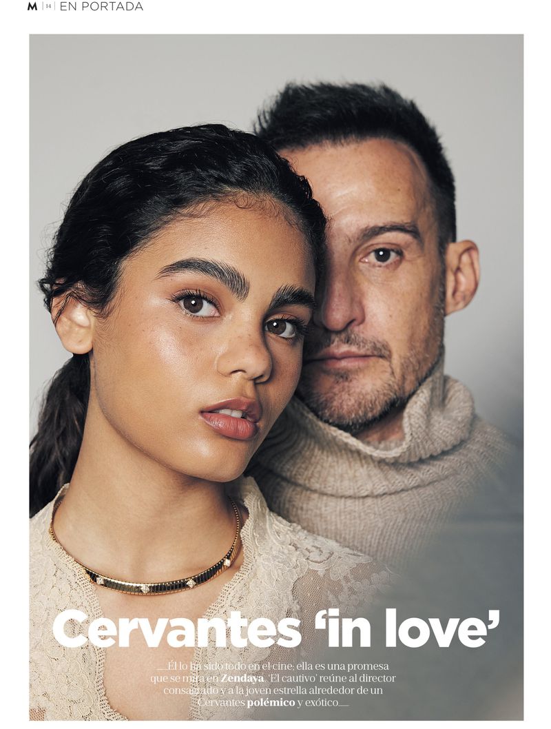 Fashion editorial photo of an adult woman with dark hair and adult man with short hair posing indoors looking at camera.