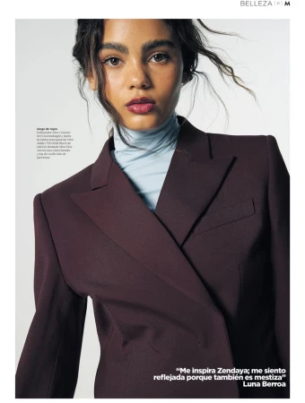 Luna Berroa wearing a deep burgundy blazer over a light blue turtleneck against a white studio background.