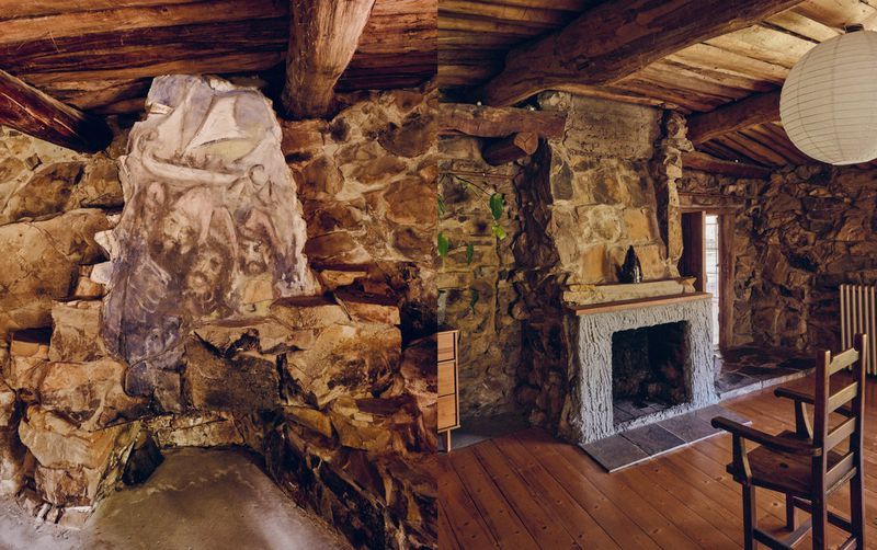 Rustic interior view showcasing stone walls, a fireplace, wooden floors and ceiling, a drawing, and ambient lighting.