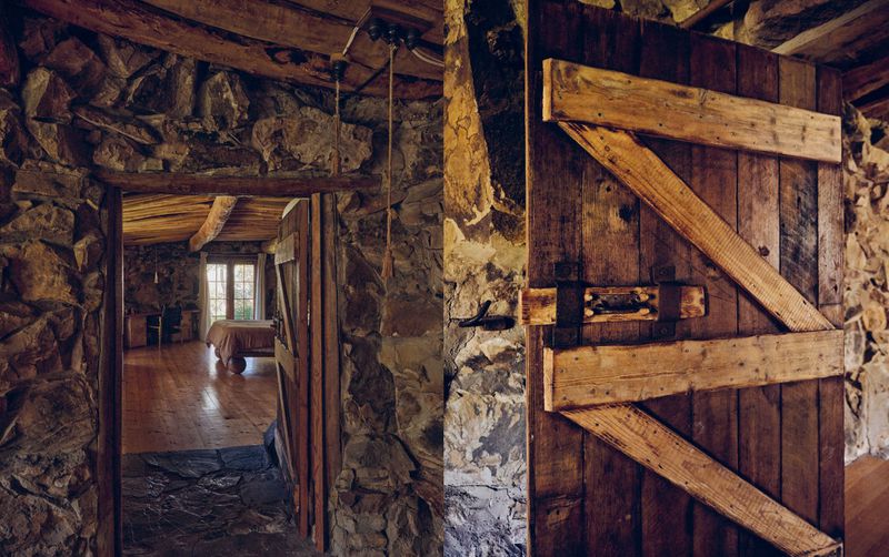 Rustic interior features a stone wall, exposed wood beams, and a weathered wooden door, complemented by warm-toned wood flooring.