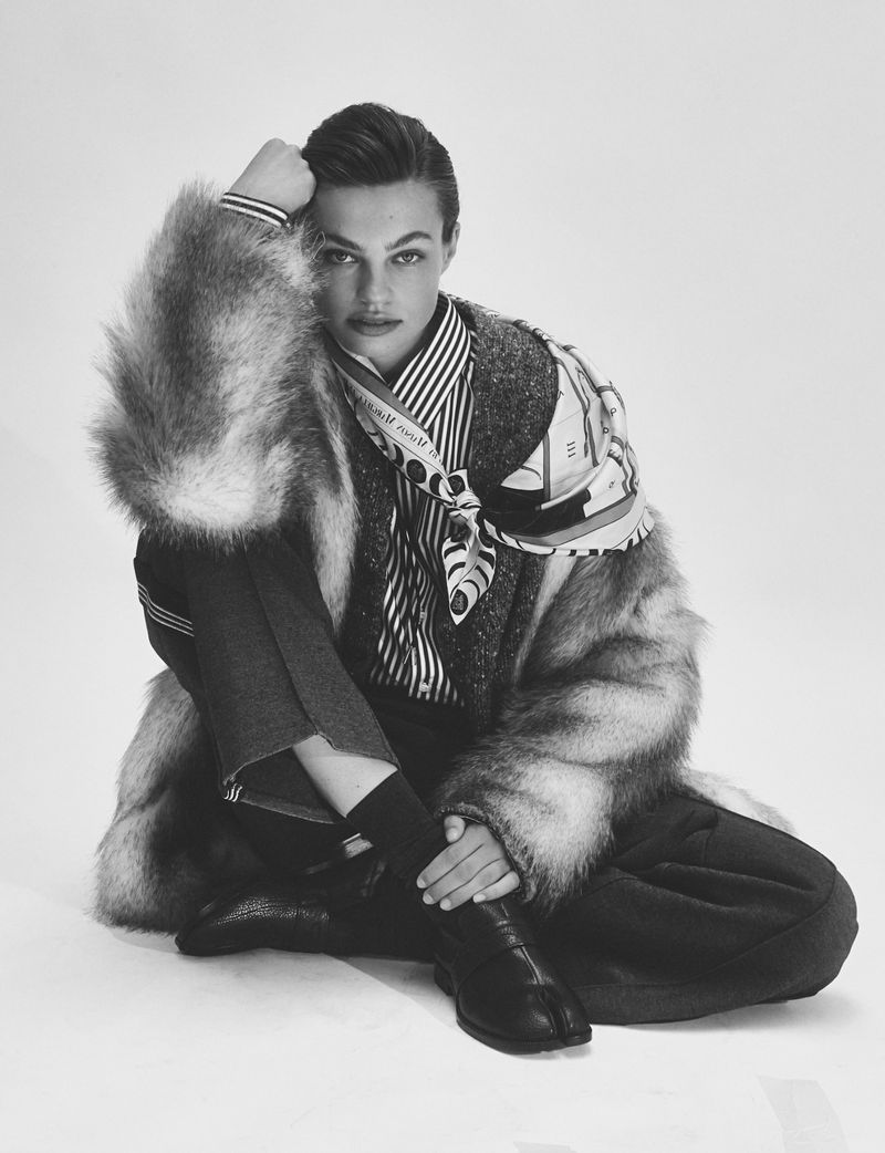 Model Anne Boomgaart seated in a fur coat, striped shirt, and patterned scarf against a white studio background for Flair Germany.