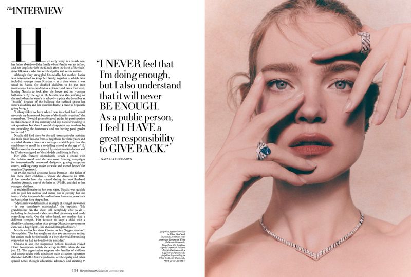 Close-up of a model wearing jewelry in a studio with text, fair skin, light hair, posing with hands near face, and neutral expression.