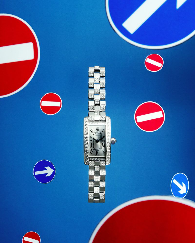 Elegant women's diamond watch featuring a silver bracelet and silver dial on a blue background with floating road signs.