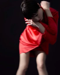 Model wearing a vibrant red dress in motion against a dark background, captured with motion blur.