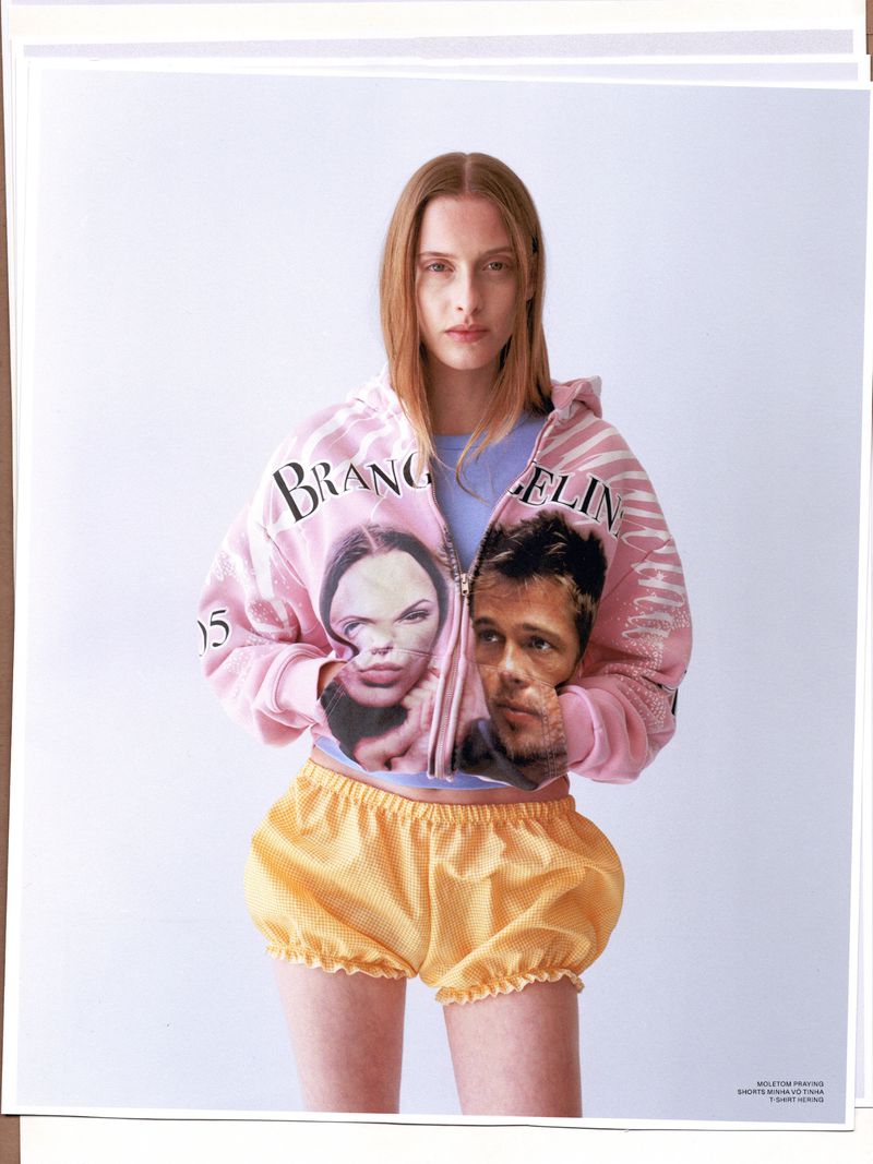 Young adult woman in pink jacket with celebrities paired with yellow polka dot bloomers against a white studio backdrop.