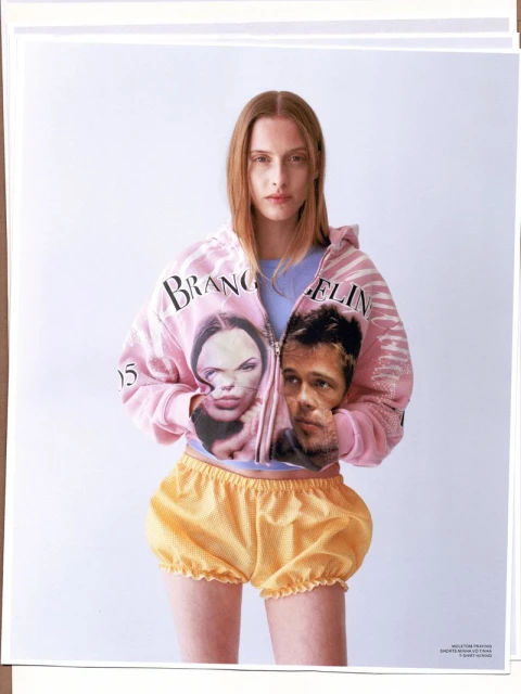 Young adult woman in pink jacket with celebrities paired with yellow polka dot bloomers against a white studio backdrop.
