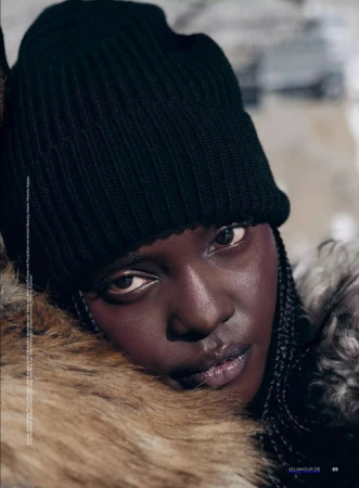 Close-up portrait of a model wearing a black ribbed beanie and a faux fur collar against an out-of-focus background