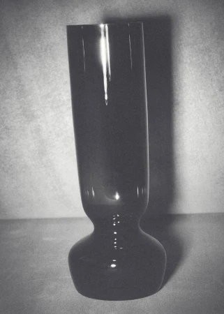Elegant tall black glass vase with glossy sheen, set against a muted background, showcasing minimalist design and subtle reflections.