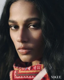 Close-up portrait of model Suganya with dark wavy hair wearing a red geometric patterned woven scarf for Vogue Philippines.
