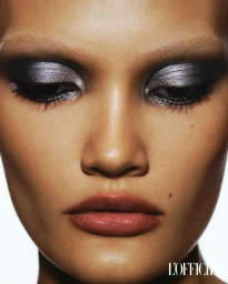 Extreme close-up beauty portrait of a woman wearing dramatic metallic silver eyeshadow, defined eyeliner, and glossy nude lips.