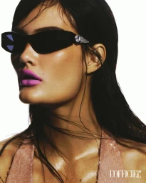 Model Yasmine Camille wearing embellished black sunglasses and bright pink lipstick against a bright white background.