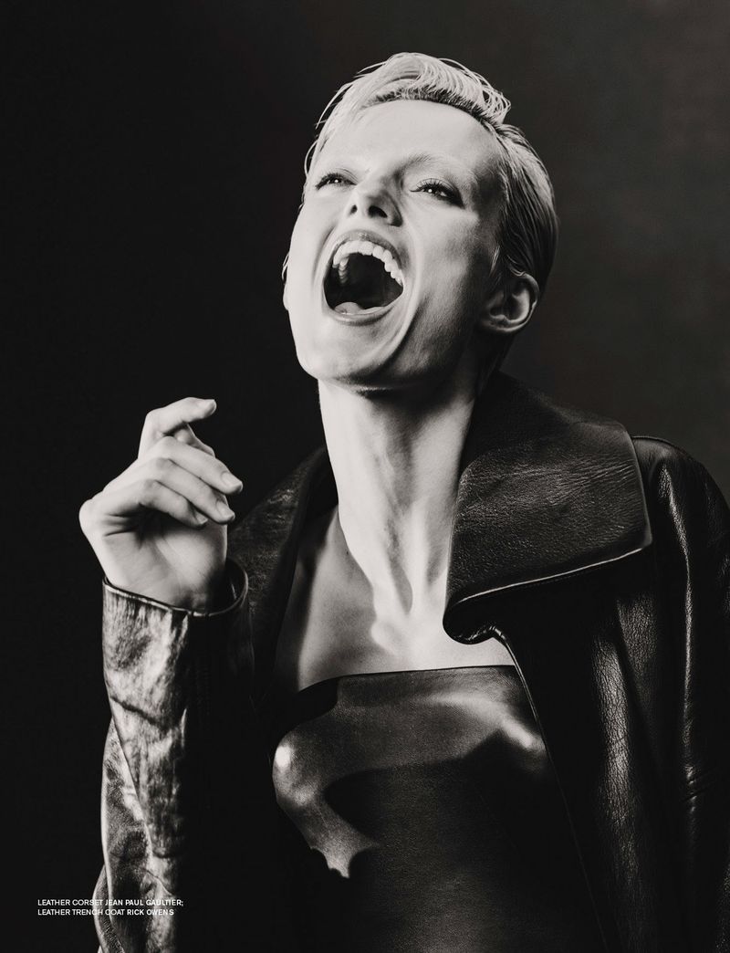 Dramatic black and white portrait of a woman with short hair wearing a leather jacket and top, captured in a photo studio setting.