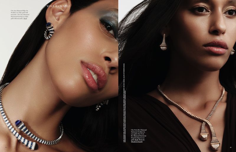 Close-up studio shot of two adult fashion models with dark hair wearing statement diamond necklaces and earrings on a neutral background.