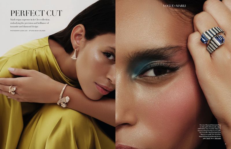 Close-up of a woman with blue eyeshadow, wearing luxury diamond jewelry including earrings, bracelet, and rings in a studio setting.