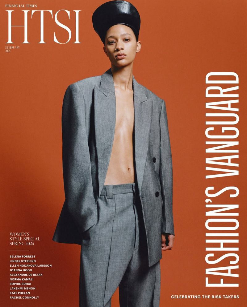 Fashion magazine cover featuring a woman in a gray suit and black cap against an orange backdrop, promoting women's style for spring 2023.