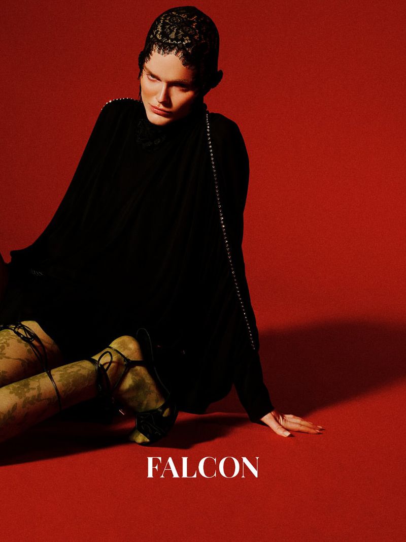 A person in a black dress and stockings poses against a red backdrop in an editorial shot. The word FALCON is printed at the bottom.