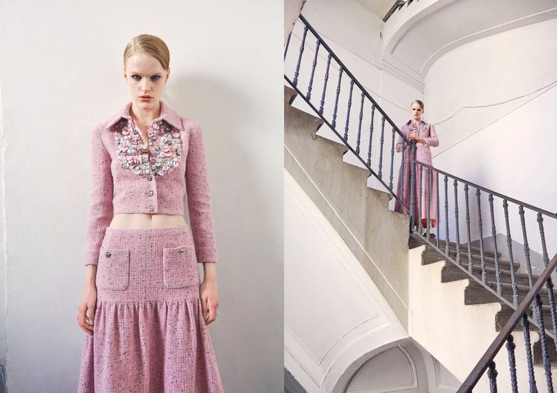 Fashion model in a pink tweed skirt suit with embellishments stands on stairs. Light pink tweed cropped jacket and maxi skirt.