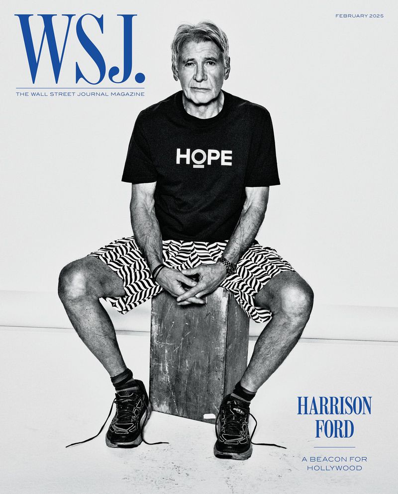 Harrison Ford poses for WSJ Magazine cover, seated on a box, wearing a black tee with the word 'HOPE' and patterned shorts.