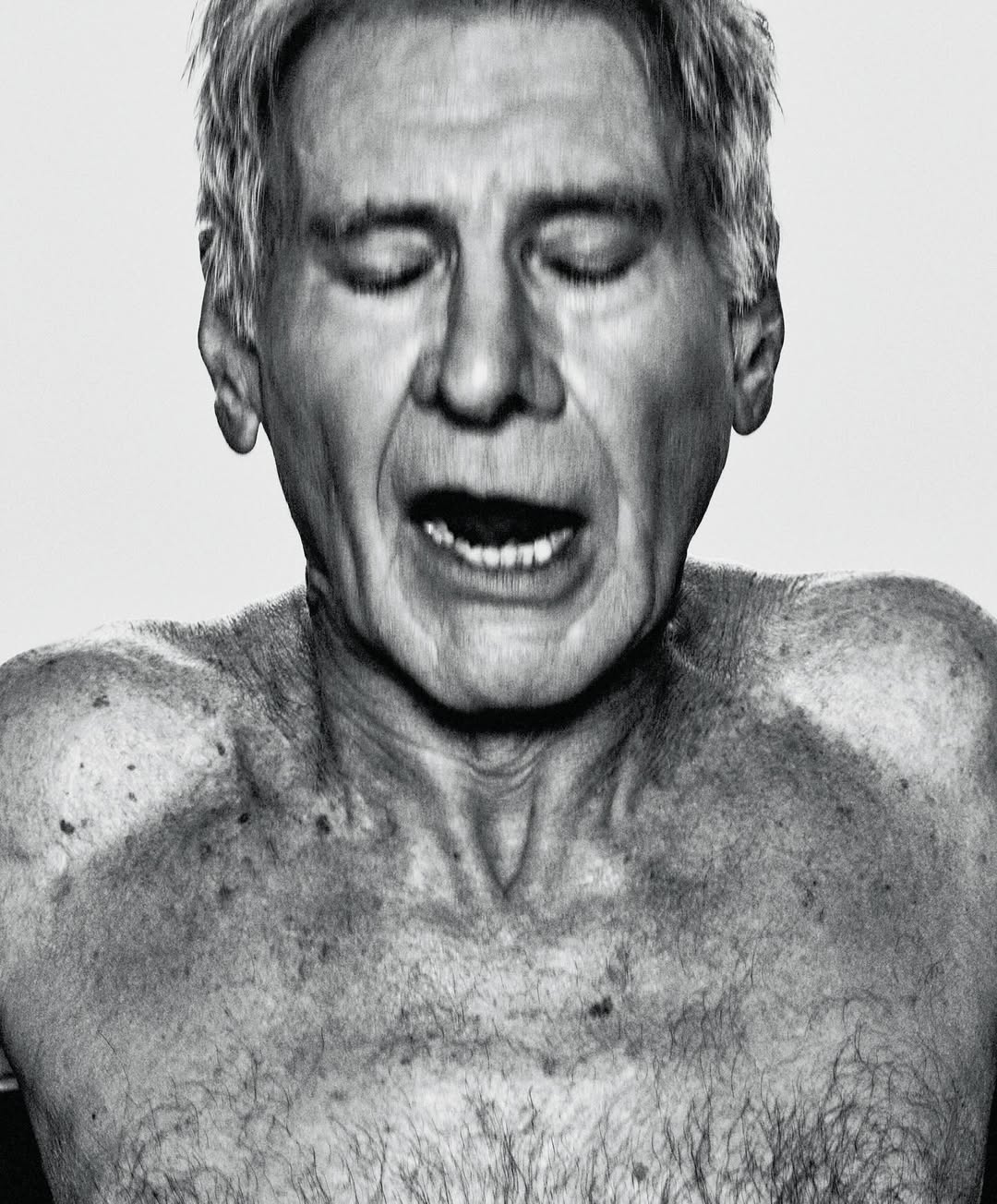 Black and white portrait of a mature adult man with closed eyes, mouth open, and torso visible against a plain white backdrop.