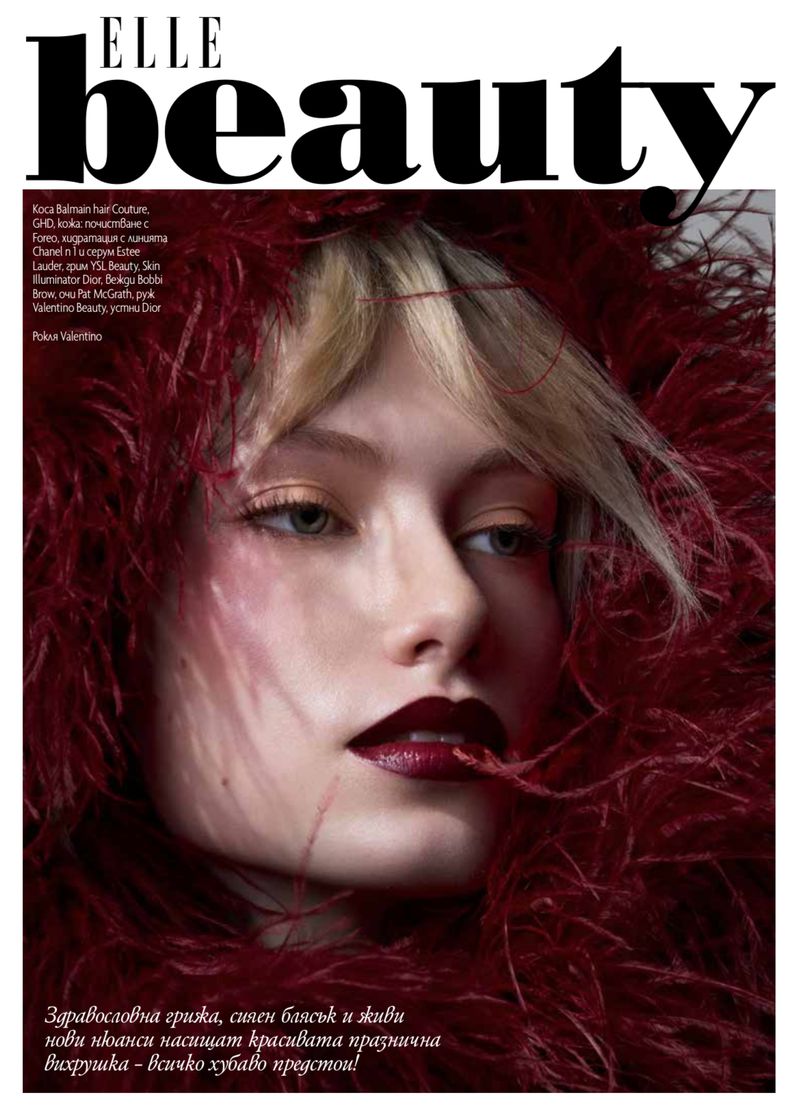 Beauty magazine cover features a woman with feathered frame, blonde hair, dark lipstick, and glowing skin for a striking portrait.