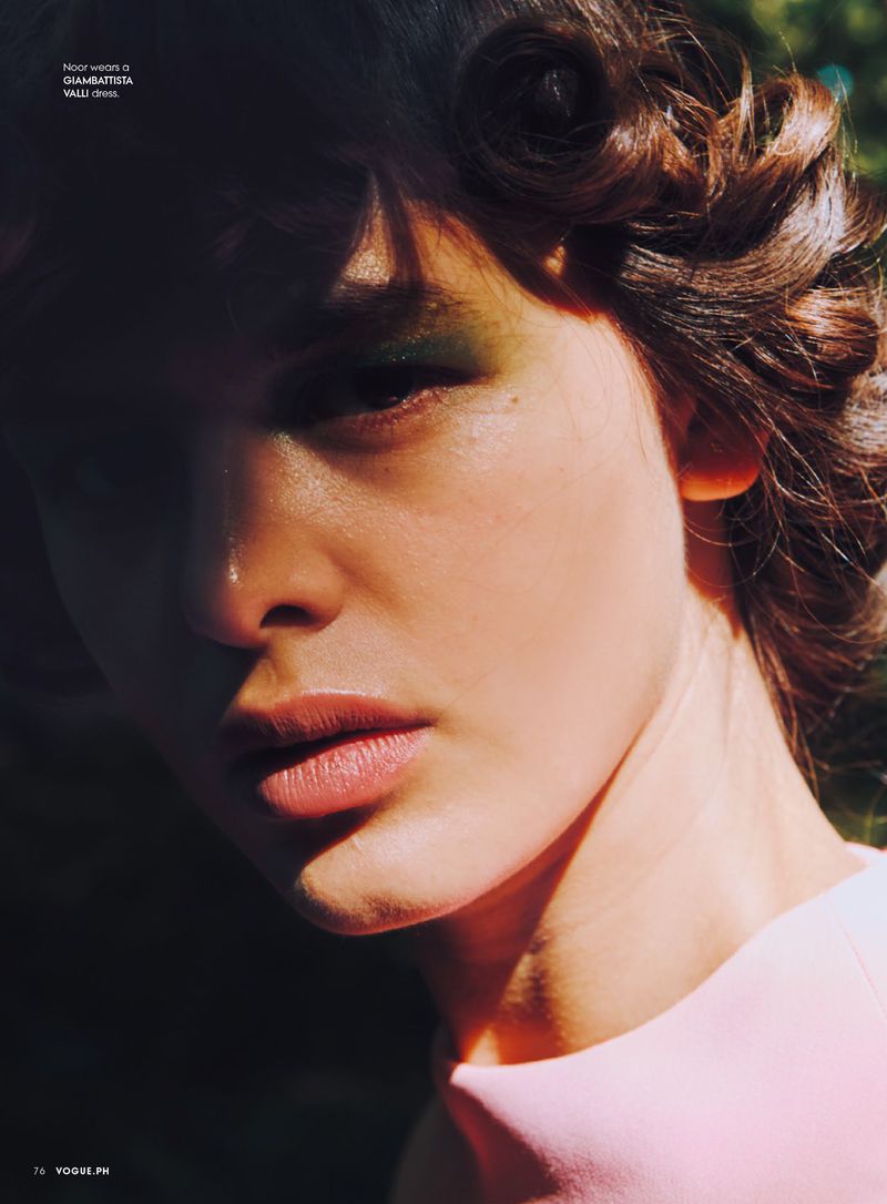 Close-up portrait of a fair-skinned adult female with wavy brown hair, wearing light green eyeshadow and a pink top, with a shadowed face.