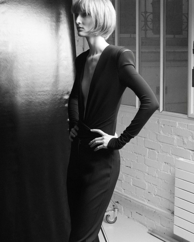 Model with bob haircut wearing black long-sleeve top standing in a studio