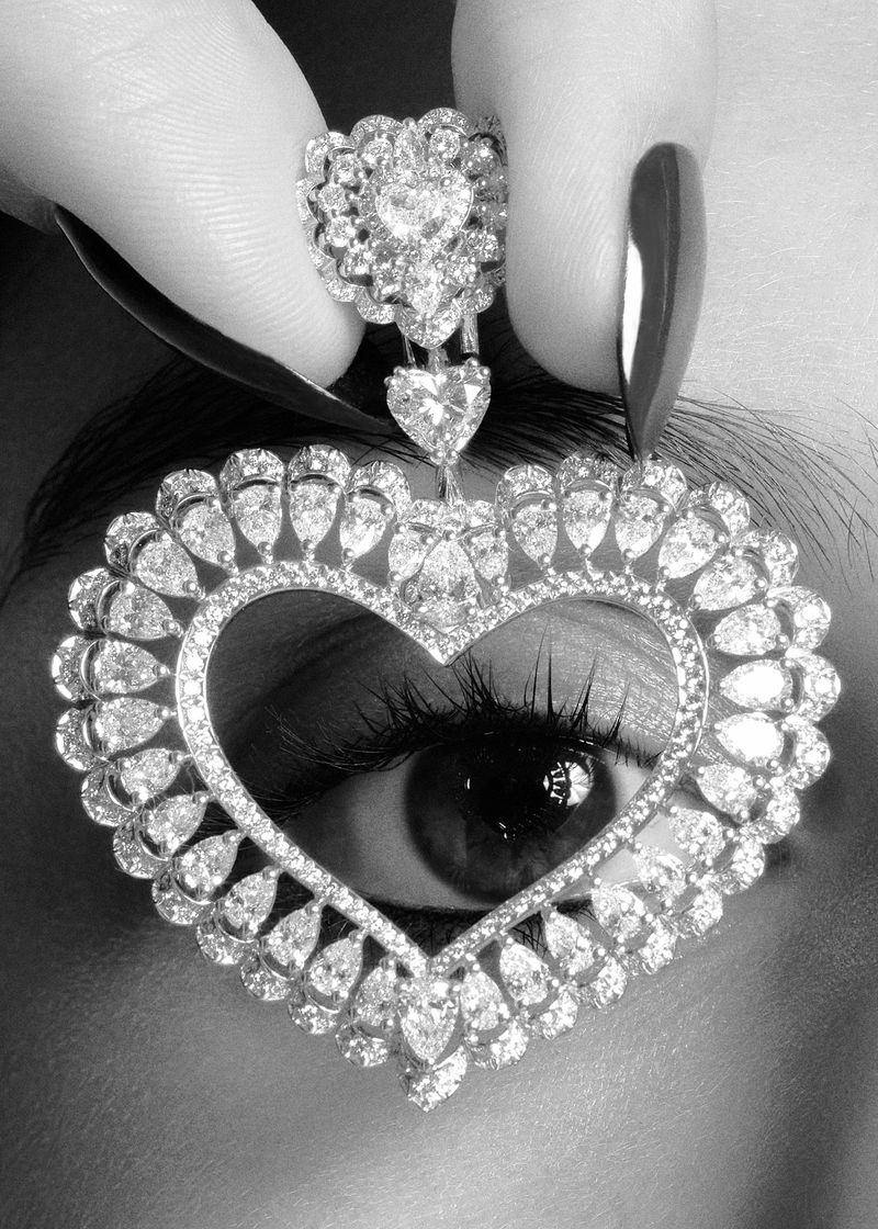 Eye-catching shot featuring a stylish woman's eye framed by an exquisite diamond heart pendant and ring, showcasing beauty and elegance.