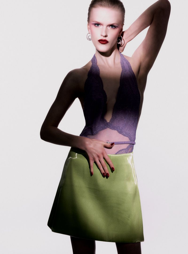 A female model poses in a purple halter top and lime green skirt against a clean white background, with studio lighting and shadow effects.