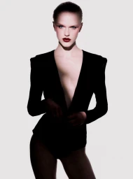 Fashion model Hannah Motler posing in a black plunging structured blazer against a plain white studio background.