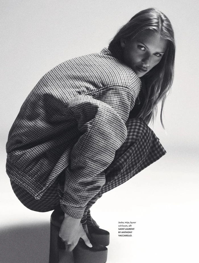Model Lea Seelenmeyer crouching in a houndstooth jacket and platform boots against a white studio background.