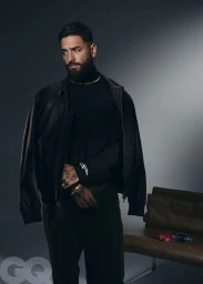 Maluma wearing a black turtleneck and leather jacket against a grey seamless studio backdrop for GQ Mexico
