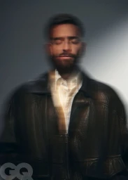 Portrait of Maluma wearing a dark leather jacket with a motion blur effect against a plain grey studio backdrop for GQ Mexico.
