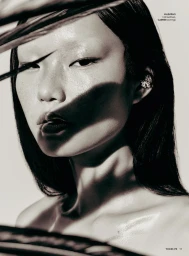 Close-up monochrome portrait of a model with dramatic shadow patterns across her face and dark hair, for Vogue Philippines.
