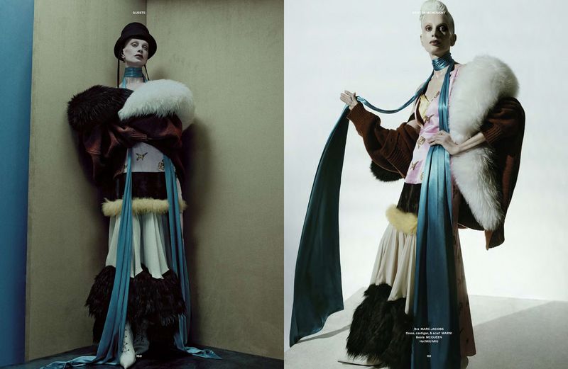 Fashion editorial featuring a thin female model in an oversized, ornate coat with fur trim, posing in a corner with a high-fashion aesthetic.