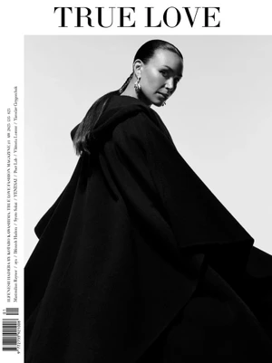 Actor Ilfenesh Hadera looking over her shoulder wearing a voluminous black hooded cloak against a clean white backdrop.