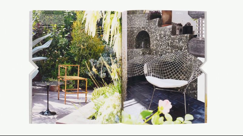 Indoor garden and patio with designer wire chair and wooden chair in a magazine, lush plants, natural light, stone textures.