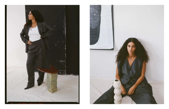 A woman with curly hair poses in a grey suit against contrasting backgrounds, creating a stylish and editorial fashion image in a photo studio.