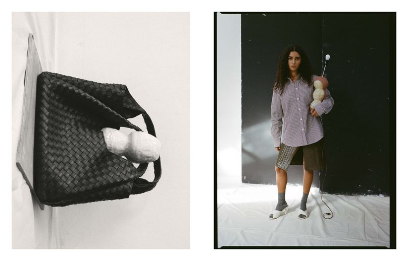 Editorial shot of a brunette woman in an oversized striped shirt holding an abstract object in a photo studio with a black and white backdrop.