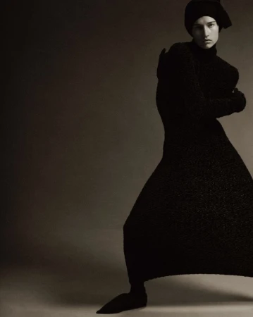 Model Apolline Rocco Fohrer wearing a black knit dress and matching headwrap against a dark studio background