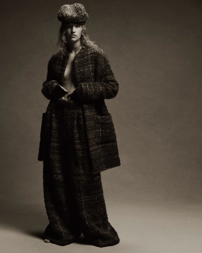 A fashion shot features an adult female model in a tweed coat, wide-leg pants, and hat, posing in a photo studio with a neutral backdrop.