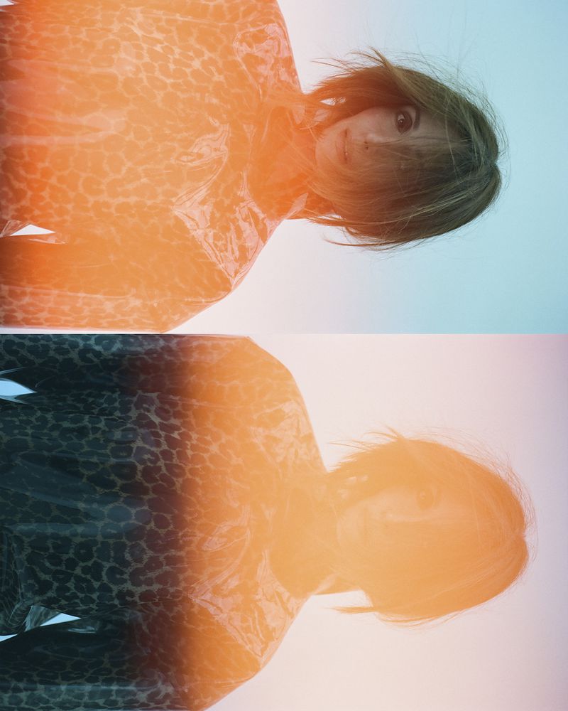 Portrait of a woman with short brown hair wearing a leopard-print top with an orange and blue gradient background in an eye-level shot.